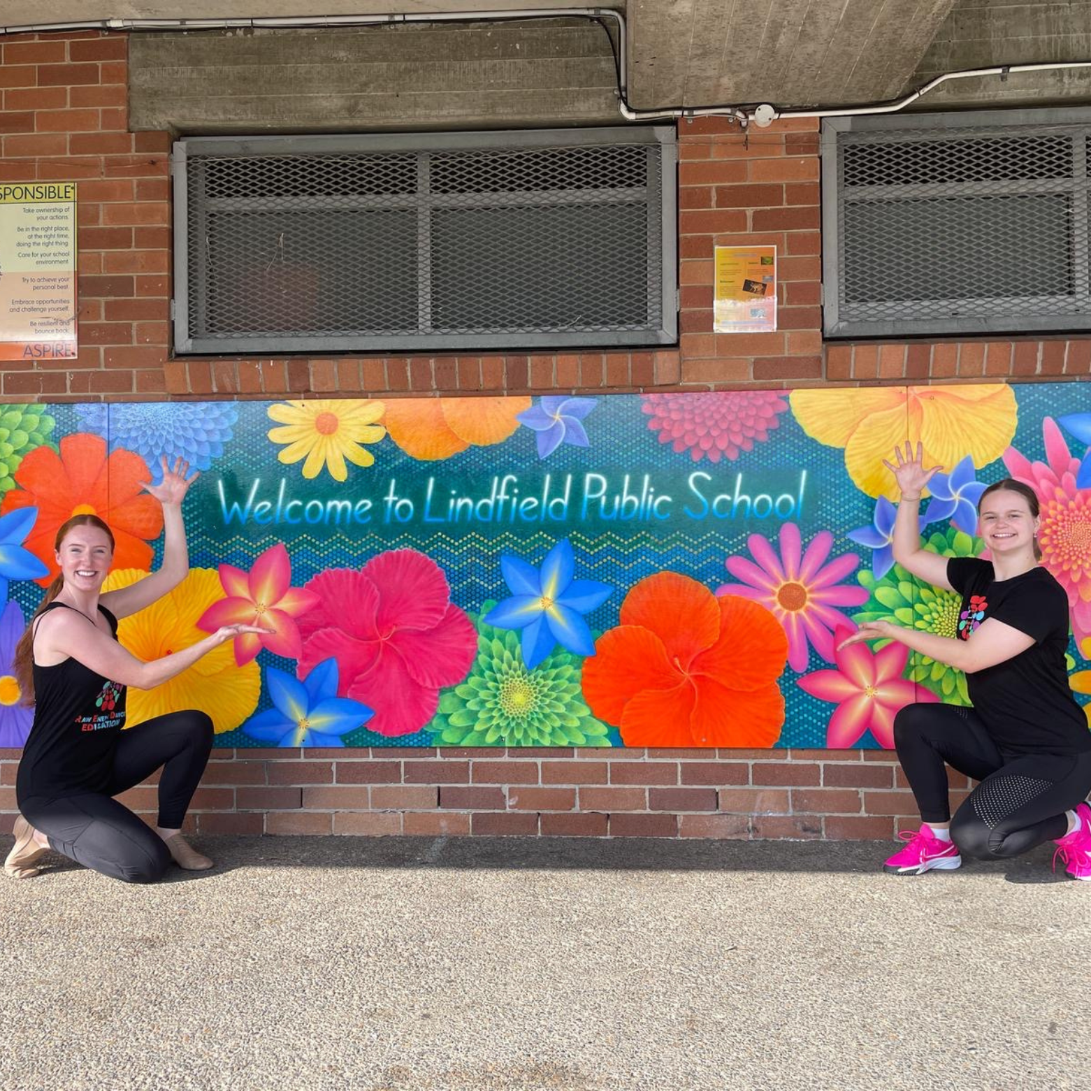 Two women next to colourful sign