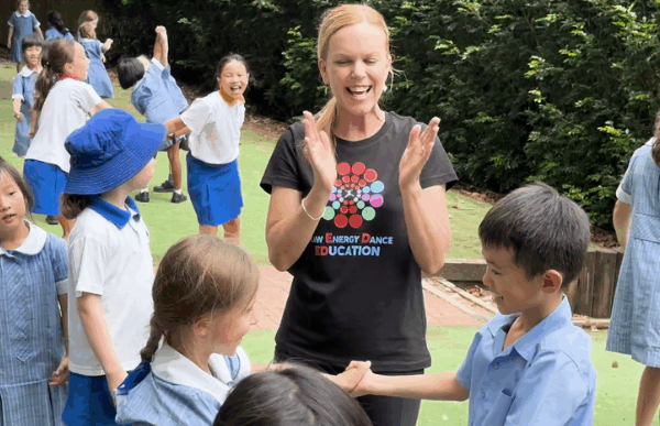 Dance instructor teaching school children is blue uniform
