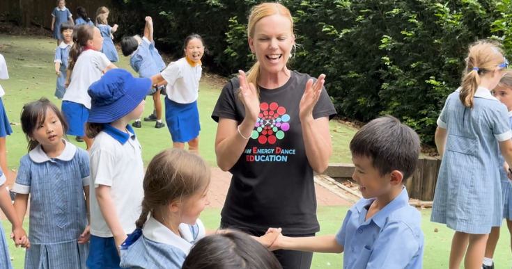 Dance instructor teaching school children is blue uniform